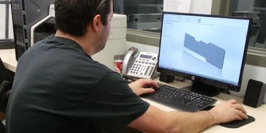 A man working on a computer in front of a monitor.