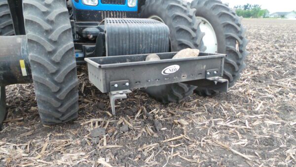 A tractor with a Rock Box for New Holland for T8 Series in the middle of a field.