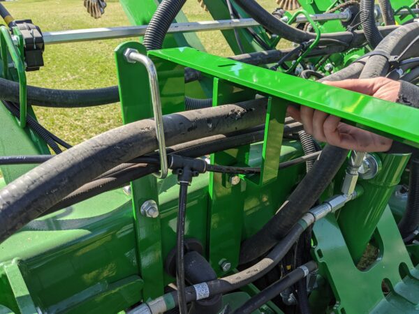 A person is holding a Large Utility Storage Box for John Deere 1790/95 Planters with Interplant on a tractor.