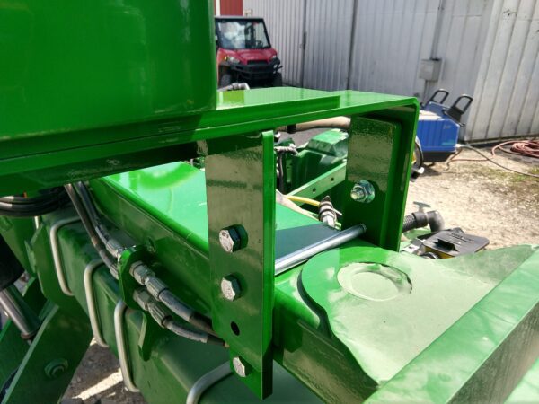 A green mounting bracket kit for a large utility box - fits Deere / Bauer Planters - with a metal handle attached to it.