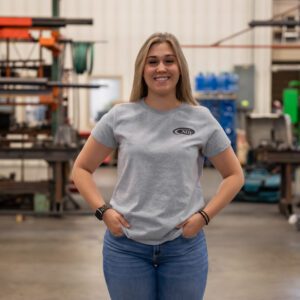 Smiling woman in industrial workshop setting.