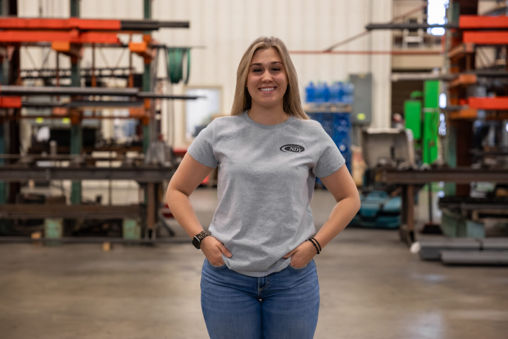 Smiling woman in industrial workshop setting.