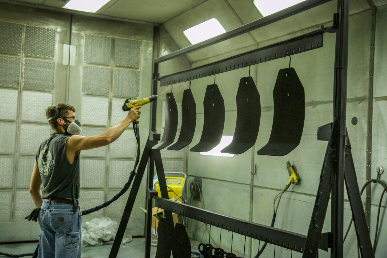 A man using a spray gun in a paint booth.