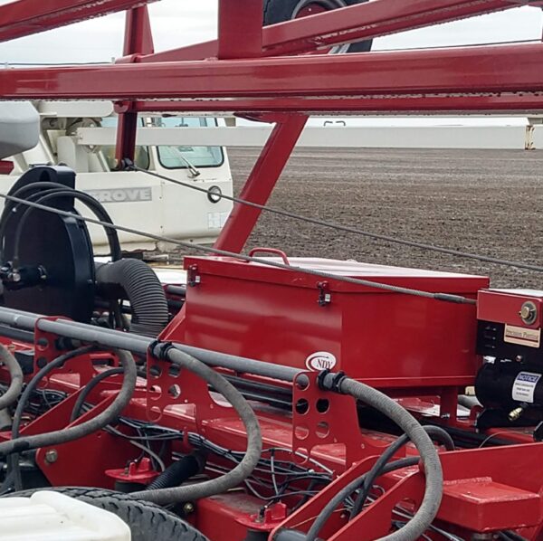 A red Large Utility Storage Box for 24 row 30" Case IH 1250/1255 Planters with hoses attached to it.