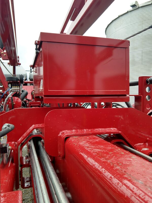 A red tractor with a Large Utility Storage Box for 24 row 30" Case IH 2150 Planters attached to it.
