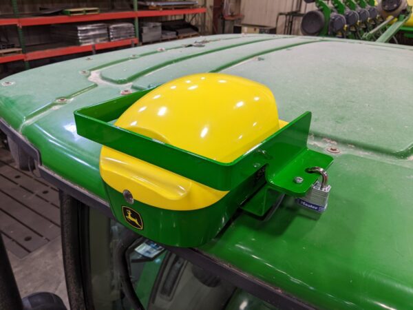 A green GPS Hinged Globe Lock for John Deere® 6000 series StarFire tractor with a yellow helmet on the hood.