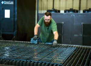 man in green tshirt working on a laser cutting machine