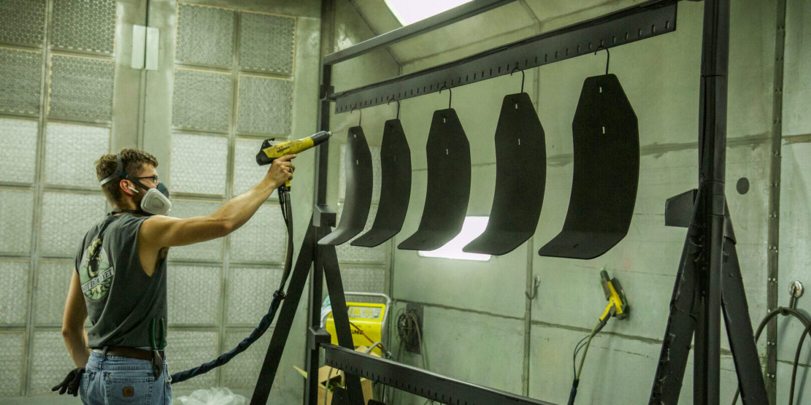 A man using a spray gun in a paint booth.